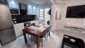 A modern kitchen with a dining area, a flat-screen TV, and a large window. - Central Apartment | Within Walking Distance of the Train Station and Downtown (alicante)