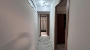 A narrow hallway with a marble floor leading to a room with a wooden door. - Central Apartment | Within Walking Distance of the Train Station and Downtown (alicante)