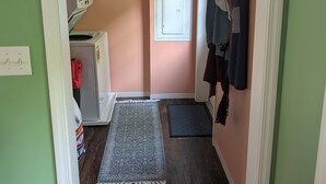 A narrow hallway with a washing machine, a drying rack, and a door with a window. - Charming 4-bedroom modular home in Summersville, WV with private creek access. (Summersville)