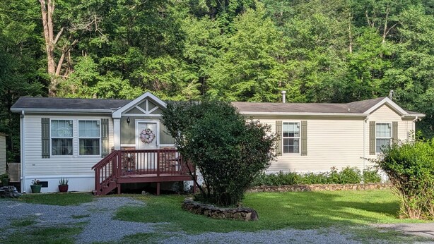 A two-story house with a front porch and a stone wall. - Charming 4-bedroom modular home in Summersville, WV with private creek access. (Summersville)
