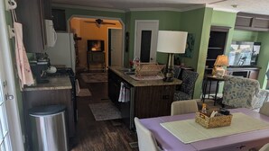 A compact kitchen with a dining area, a small island, and a TV in the background. - Charming 4-bedroom modular home in Summersville, WV with private creek access. (Summersville)
