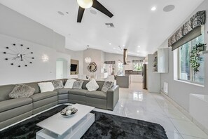 Ein modernes Wohnzimmer mit einem Ecksofa, einem Couchtisch und einer großen Wanduhr.