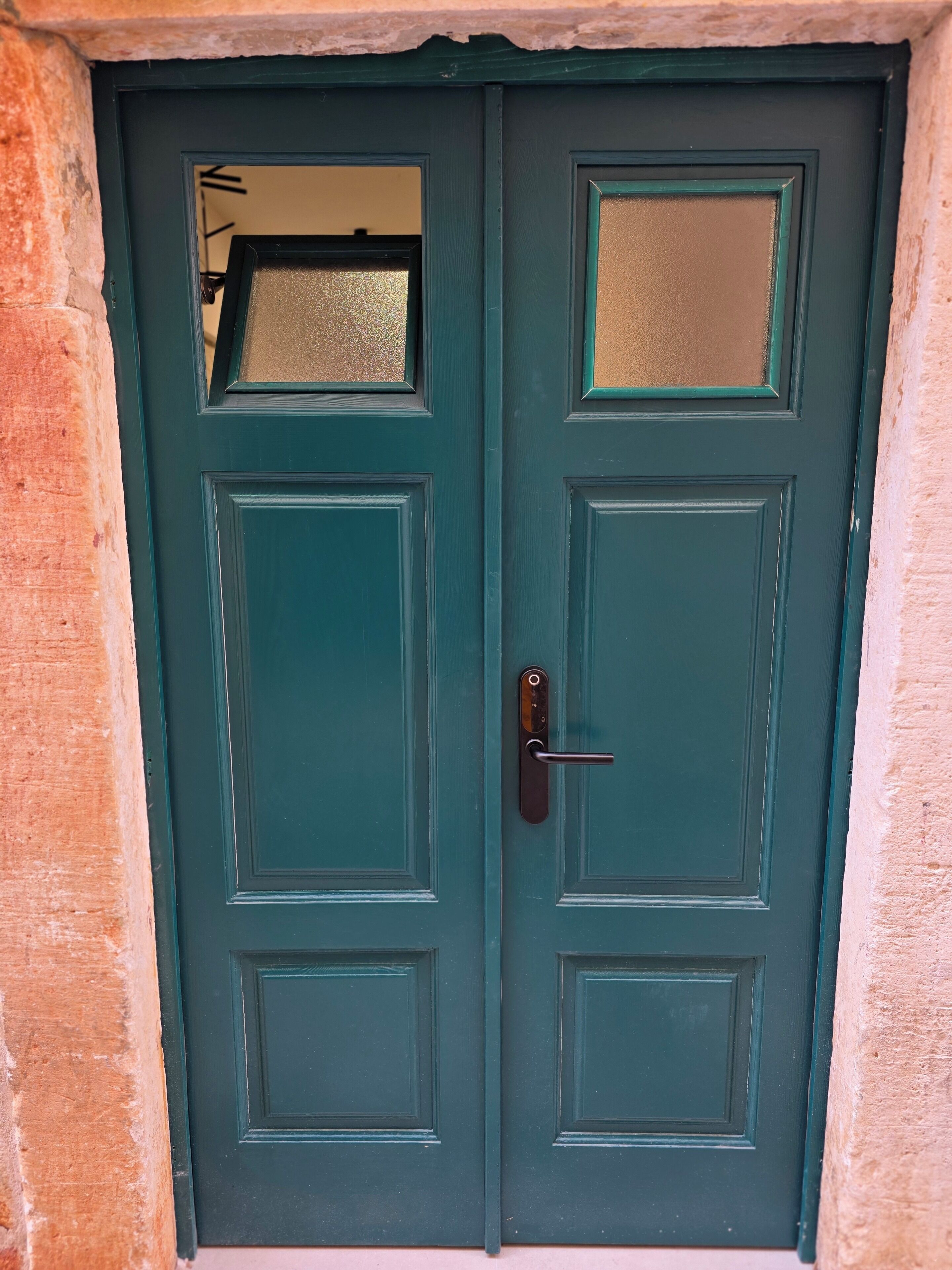 A double door with a keyhole and a handle, set in a stone wall.