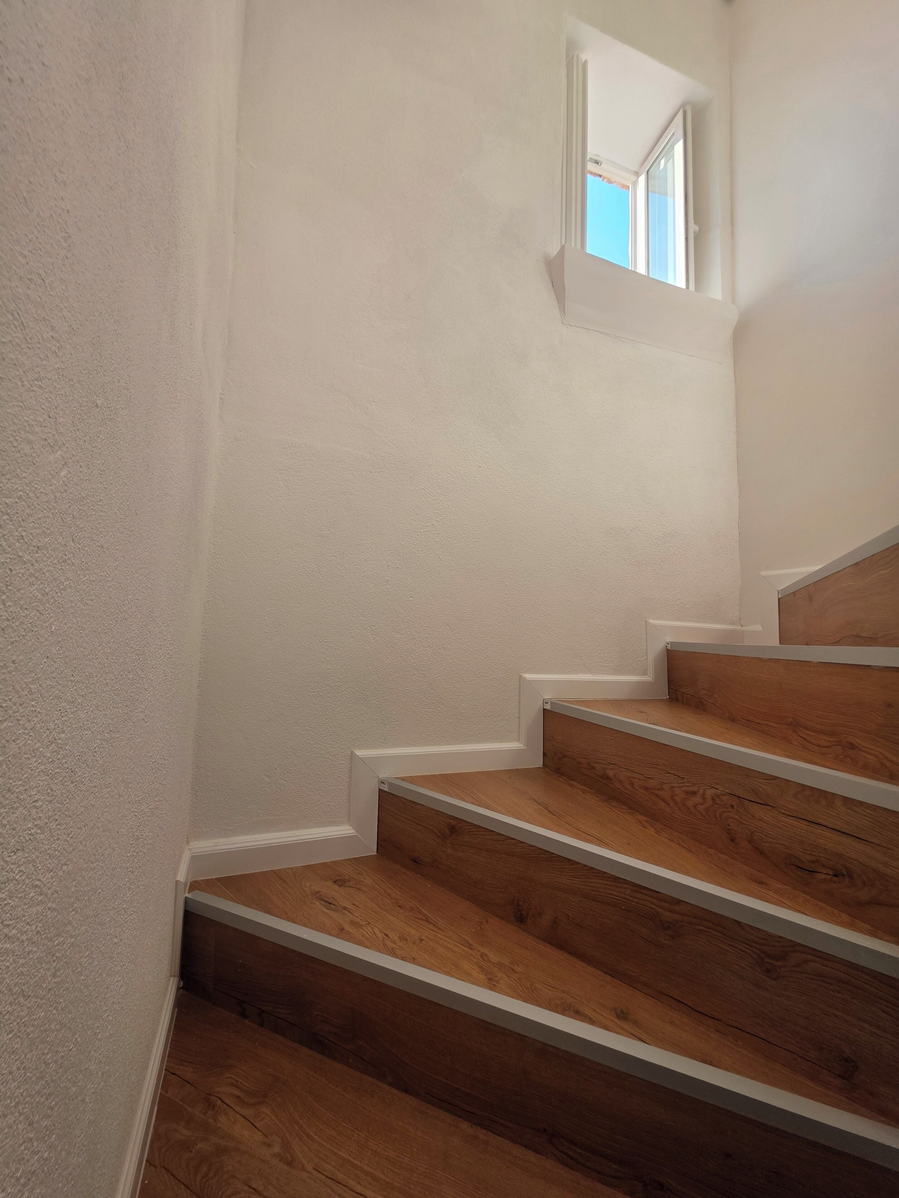 A staircase with wooden steps and white walls.