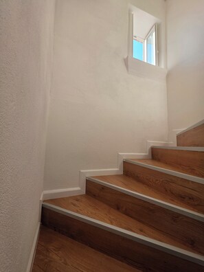 Una escalera con escalones de madera y paredes blancas.