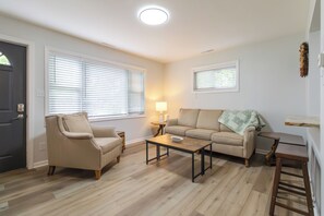 En stue med sofa, lænestol, sofabord og en lampe.