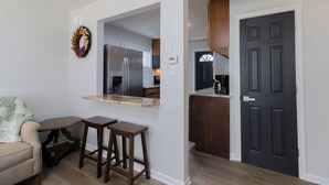 A modern kitchen with a built-in refrigerator, a dark wooden door, and a small island with stools. - Entire Hobart Home (Hobart)