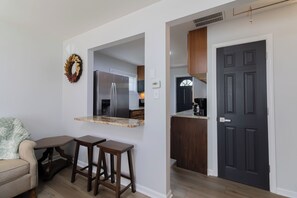 A modern kitchen with a built-in refrigerator, a dark wooden door, and a small island with stools. - Entire Hobart Home (Hobart)
