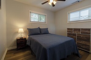 A bedroom with a bed, a nightstand, a dresser, and two windows with blinds. - Entire Hobart Home (Hobart)