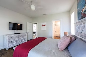 Ein Schlafzimmer mit Bett, Schminktisch, Fernseher und einer Tür zu einem Badezimmer.