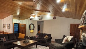 A cozy living room with wooden ceiling beams, a fireplace, and a large mirror on the wall. - Adorable 3-bedroom cabin in Pinetop Country Club, newly renovated. Pets Welcome! (Pinetop Country Club)