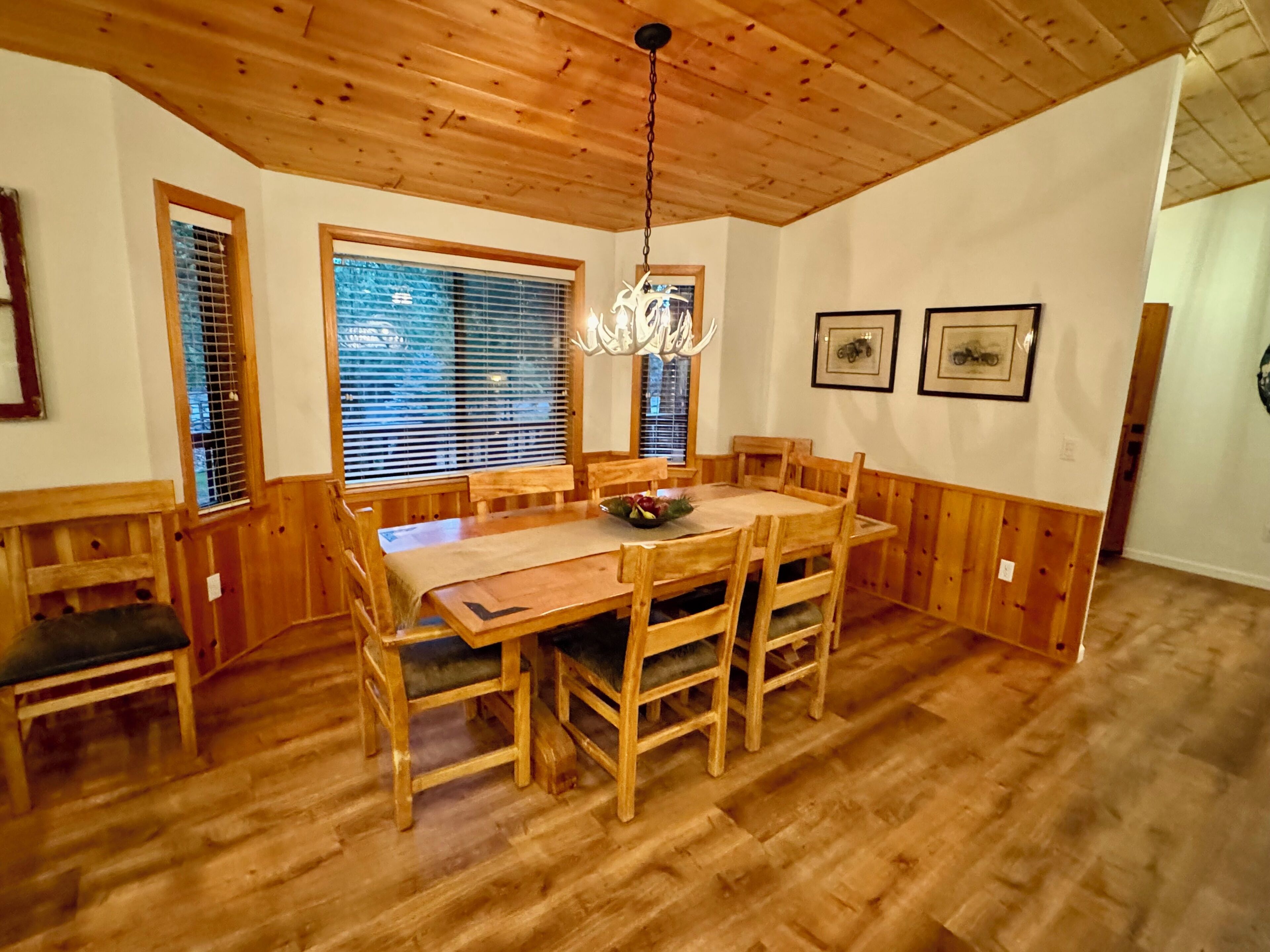 A wooden dining area with a table and chairs, a chandelier, and framed pictures on the wall.