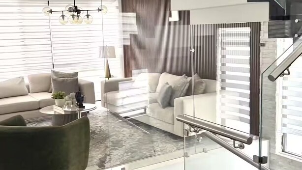 Ein modernes Wohnzimmer mit Wendeltreppe aus Glas, einer Couch, einem Couchtisch und einem Kronleuchter.