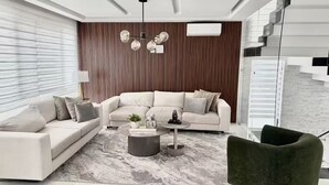 A modern living room with a sectional sofa, a round coffee table, and a green armchair.