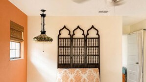 Ein Zimmer mit Deckenventilator, einer gemusterten Sitzbank, einer dekorativen Wandverkleidung und einer Pendelleuchte.