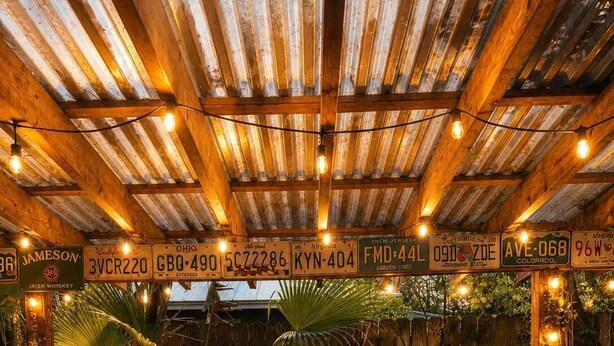 Eine rustikale Bar mit Holzbalkendecke, Vintage-Kennzeichen zur Dekoration und einer Holztresore.