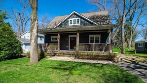 A two-story house with a front porch, a small front yard, and a driveway. - Casa Sul Lago Spacious 5-bedroom house in charming Delavan w/AC Firepit Deck (Delavan)