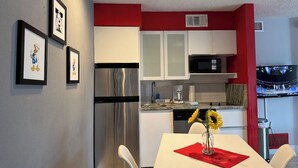 Una cocina moderna con armarios blancos, un refrigerador de acero inoxidable y un microondas.