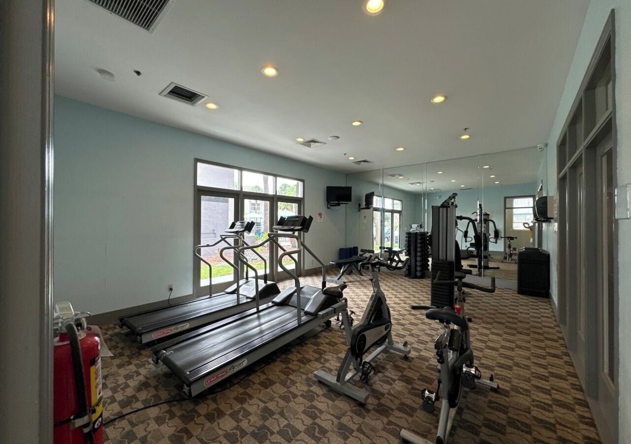 Un gimnasio con cintas de correr, elípticas y equipo de pesas.
