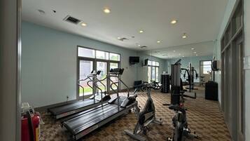 Un gimnasio con cintas de correr, elípticas y equipo de pesas.