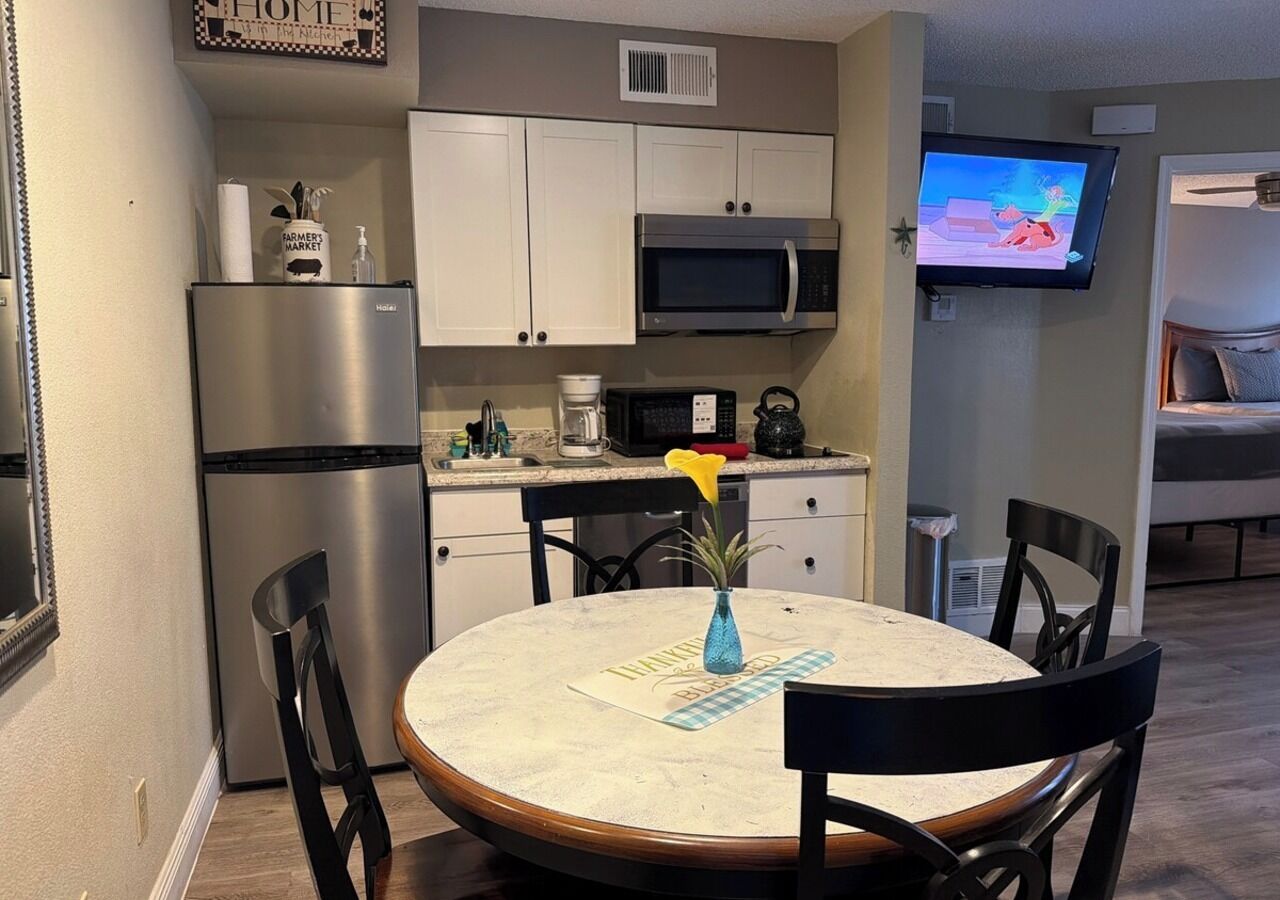 A compact kitchen with a microwave, refrigerator, and a dining area with a table and chairs.