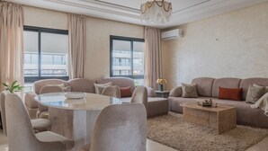Un soggiorno moderno con un tavolo rotondo in vetro, divani beige e un tavolino da caffè in legno.
