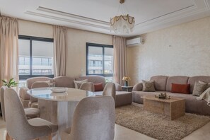 A modern living room with a round glass table, beige sofas, and a wooden coffee table. - Stunning New 3BR/2BA | Steps to TGV Station, Hilton & Tangier Corniche (Tanger)