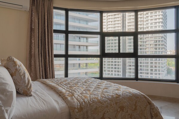A hotel room with a large window, a bed with a patterned bedspread, and a curtain. - Stunning New 3BR/2BA | Steps to TGV Station, Hilton & Tangier Corniche (Tanger)