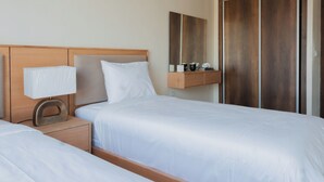 Una camera d'albergo con un letto, comodino, lampada e specchio.