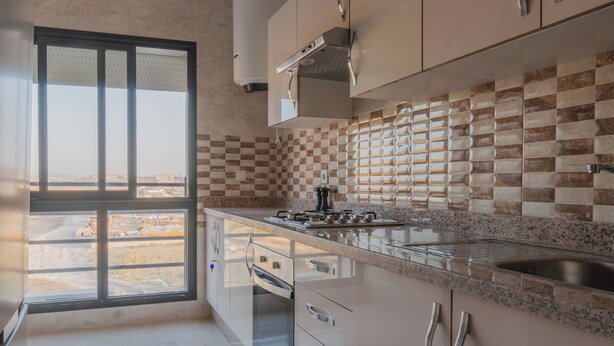 Una cucina moderna con un'ampia finestra, un piano di lavoro in granito, elettrodomestici in acciaio inossidabile e una parete divisoria a scacchi.