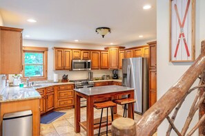 A kitchen with wooden cabinets, stainless steel appliances, and a large window. - Jay Brook Lodge | Sleeps 16 | Hot Tub | Game Room (Jay)