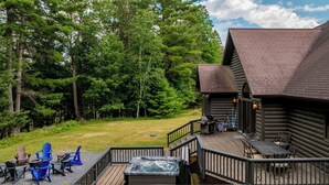 A log cabin with a deck, outdoor seating, and a hot tub. - Jay Brook Lodge | Sleeps 16 | Hot Tub | Game Room (Jay)