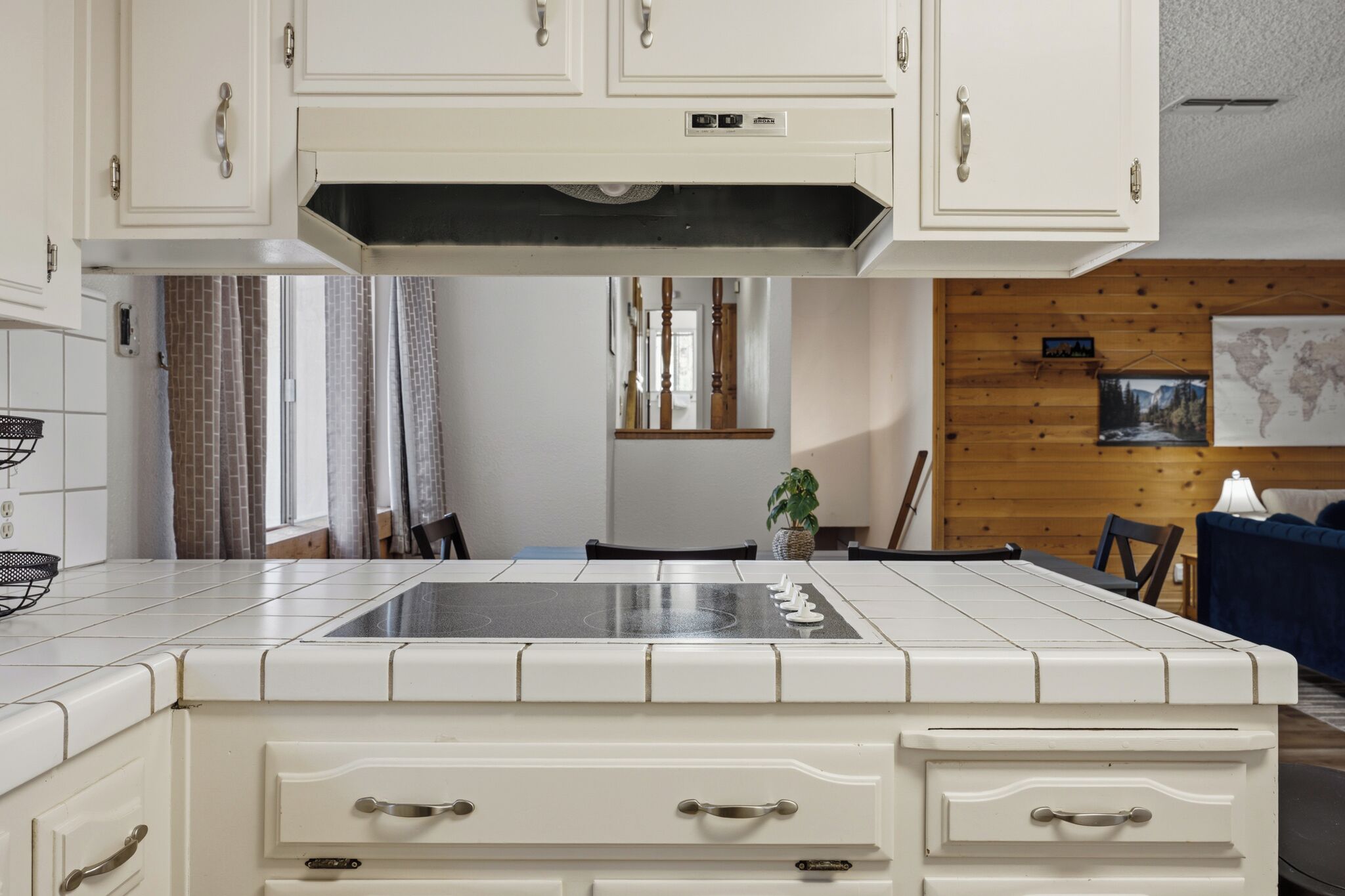 Une cuisine avec des meubles blancs, une cuisinière et un coin repas comprenant des chaises et une table.