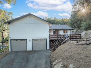 A two-story building with a garage, a staircase, and a deck. - Buckeye Ranch: Lovely mountain house/ 20 min from Yosemite/ 6 min from Bass lake (Oakhurst)