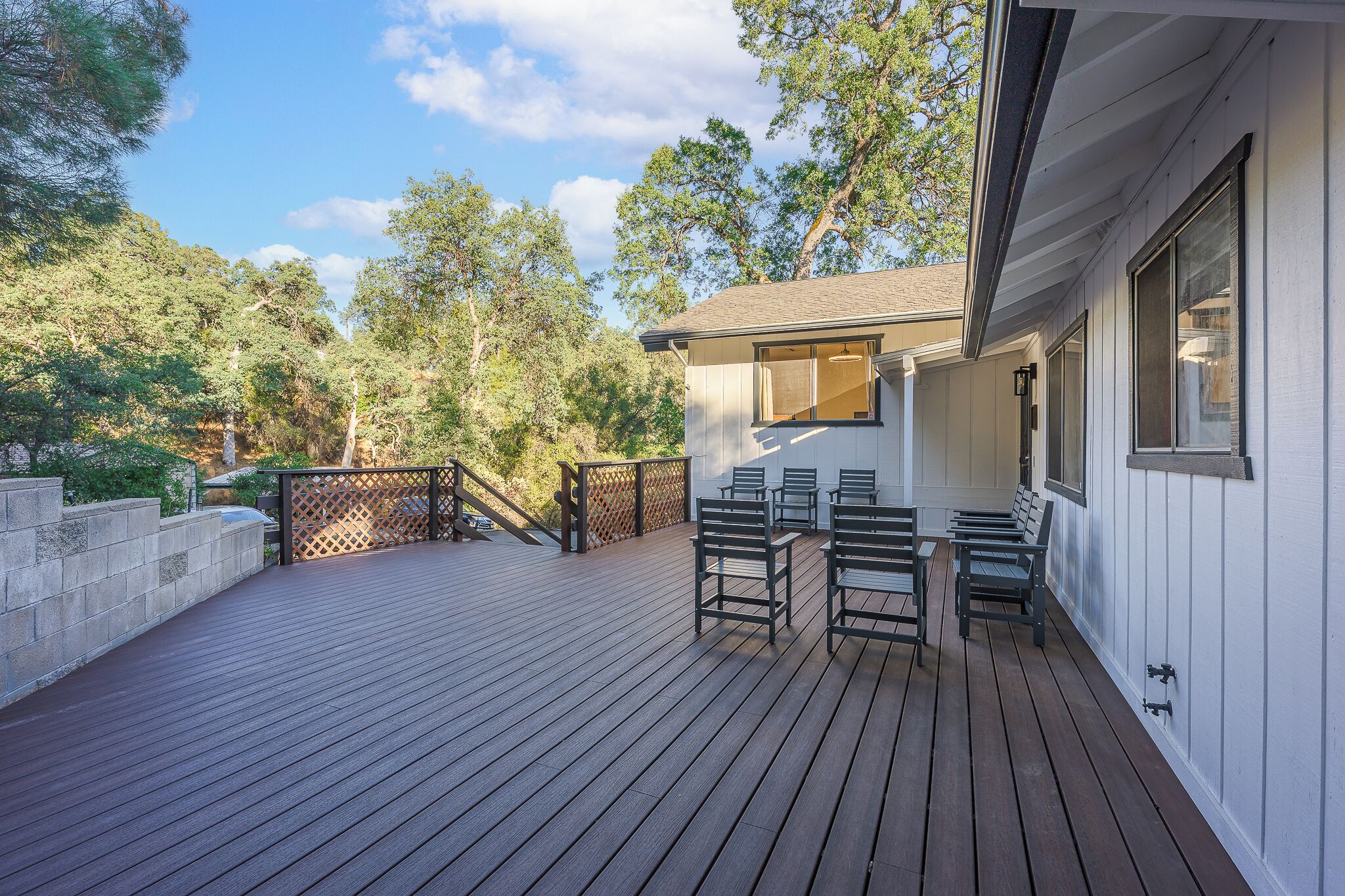 Une terrasse en bois avec des sièges extérieurs et une vue sur les arbres.