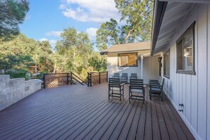 Eine Holzterrasse mit Sitzgelegenheit und Blick auf Bäume.