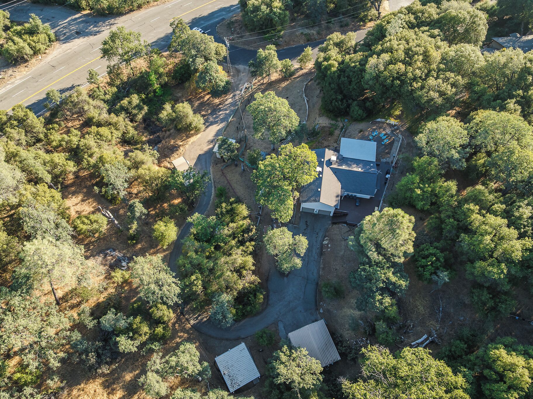 An aerial view of a property with a main building, a smaller structure, and a paved driveway.