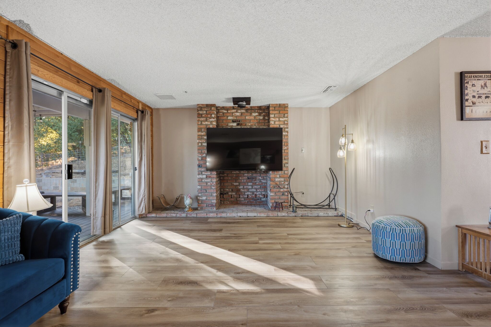 Un salon spacieux avec une cheminée en briques, un grand téléviseur à écran plat et un plancher en bois.