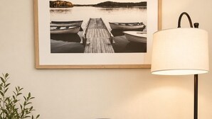 Una poltrona blu con un cuscino, una lampada da terra, una fotografia incorniciata al muro e una pianta in vaso.