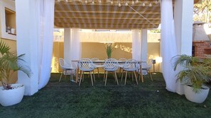 Eine Terrasse im Freien mit Tisch und Stühlen, umgeben von weißen Säulen und einer Holzbeschichtung.
