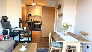 Una sala de estar moderna con un sofá, una mesa de comedor de madera y una cocina al fondo.