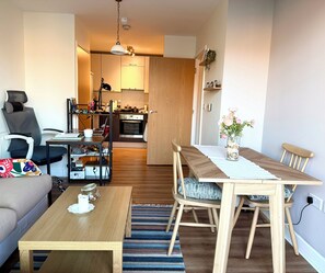 Ein modernes Wohnzimmer mit einer Couch, einem Holzespeisetisch und einer Küche im Hintergrund.