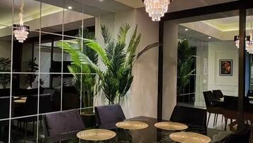 A dining area with a large table, black chairs, and two chandeliers.