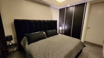 Une chambre à coucher avec un lit, une table de chevet, une lampe, une armoire et une porte.