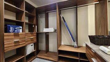 Un dressing avec des étagères en bois, une tringle à vêtements et une petite table sur laquelle est posé un panier.