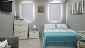 Ein Schlafzimmer mit Bett, Nachttisch, Kommode, Fernseher und Fenster.