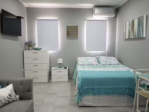 Ein Schlafzimmer mit Bett, Nachttisch, Kommode, Fernseher und Fenster.