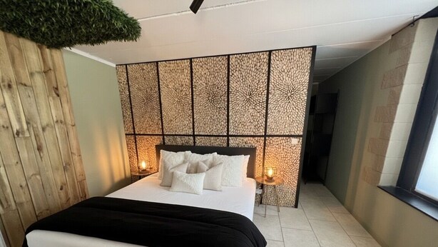 A modern bedroom with a bed, a decorative headboard, and a window.