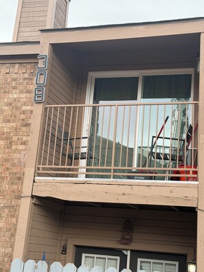 Un edificio de dos pisos con balcón, fachada de ladrillo y una ventana visible.