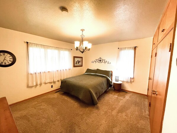 A bedroom with a bed, a clock, a chandelier, and a door.